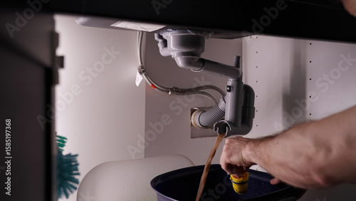 Plumber releasing drain pipe of clogged kitchen sink waste water