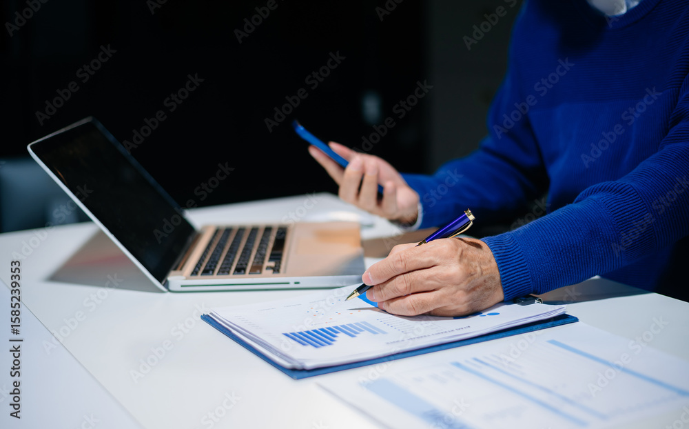 Fototapeta premium business documents on office desk with laptop and smart phone and graph business diagram and man working