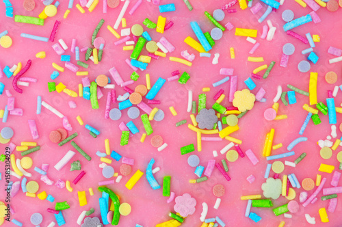 Fotografija Pink icing with scattered unicorn confetti shapes sugar cake decoration backgrou