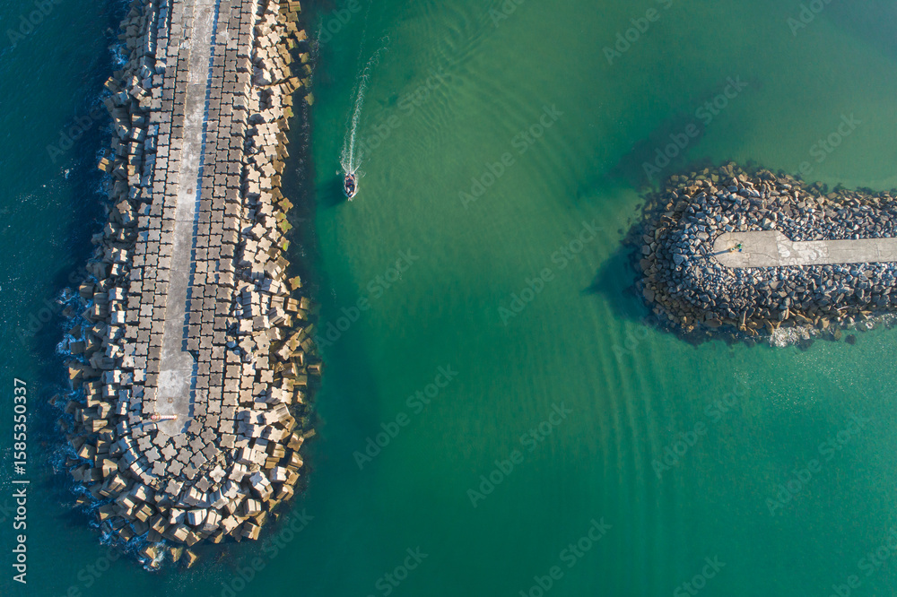 Obraz premium Commercial and Recreational Boating Hub Aerial View of a Stone Jetty Extending into Green Sea, aerial drone top down view