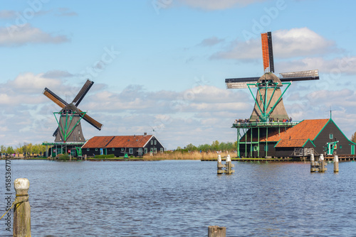 View of old Dutch windmills on a lake against a blue sky in Holland. Zaanse Schans, Zaanstad, province North Holland, Netherlands.