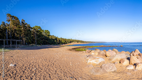 Billede på lærred Sunlit panorama of Komarovo's Baltic coast: glacial boulders on textured sandy beach with footprints