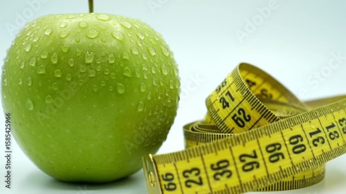 Green apple with measuring tape isolated on white, symbolizing healthy diet, weight loss, and fitness lifestyle