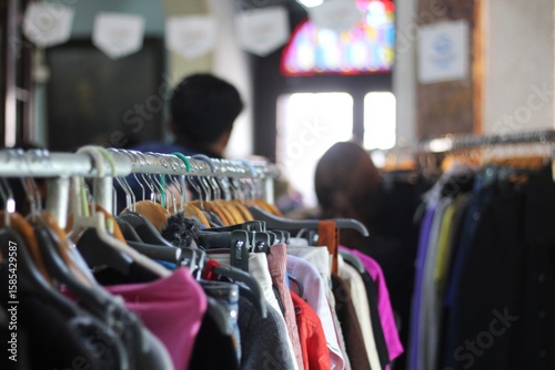 Roupas em cabides na feira de moda circular em economia sustentável com pessoas desfocadas ao fundo