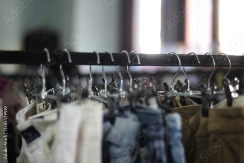 Roupas usadas em cabides na feira de moda circular com fundo desfocado.