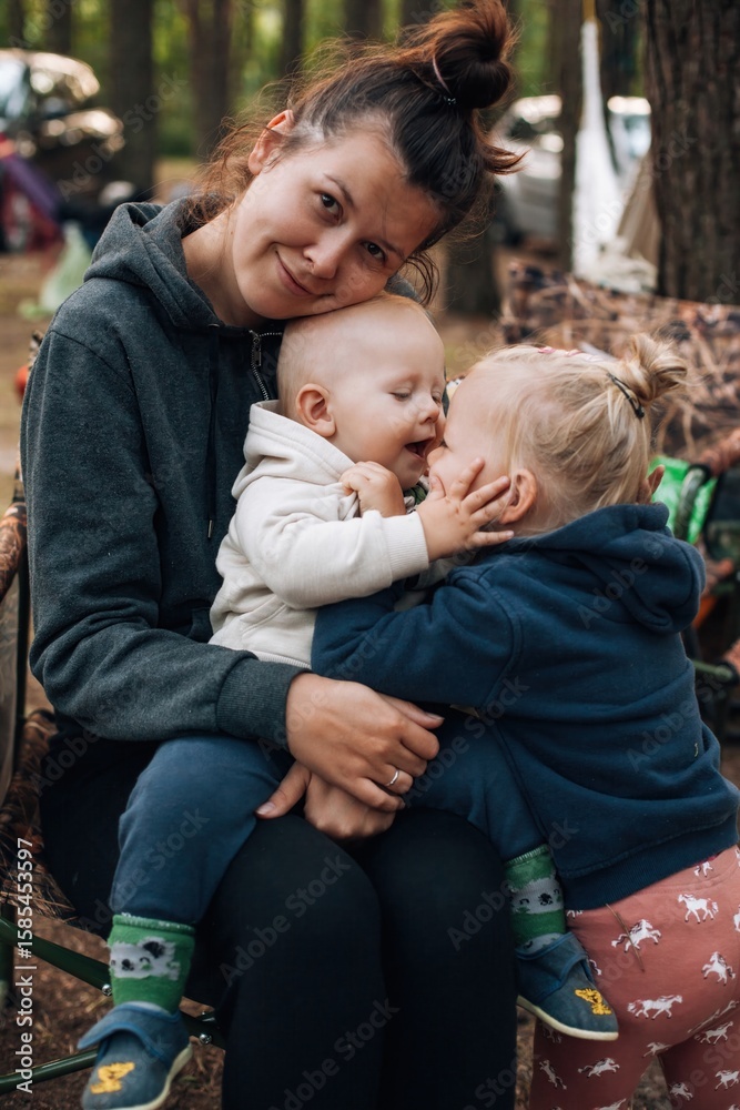 Fototapeta premium Mother hugging and playing with her two children on camping holiday