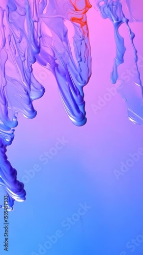 Vibrant purple and blue liquid paint flows downward creating mesmerizing abstract patterns as colors blend and swirl together in smooth fluid motion against gradient background