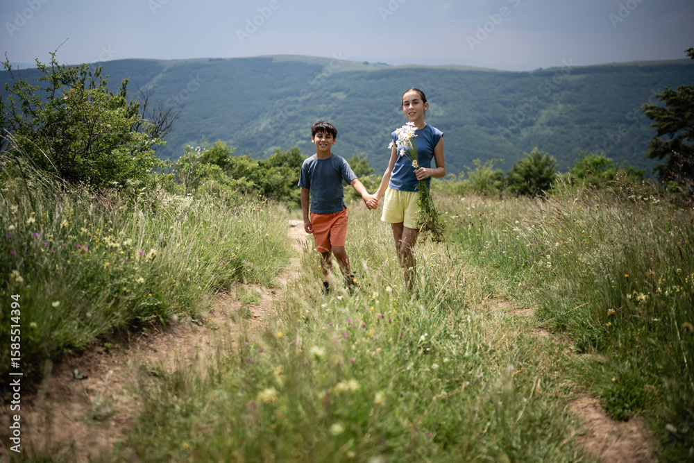 Fototapeta premium Brother and sister holding hands walking on country path