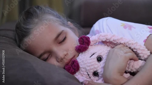 child girl sleeps on the couch hugging a plush toy