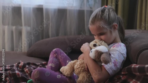 Sad child girl depression  with toys is sitting on the couch.