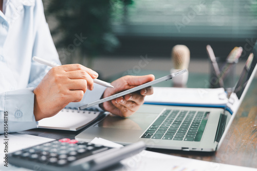 Office businesswoman hand to operate calculator analyzing financial data, counting costs on desk. accounting, financial analysis for business budget planning, calculation support, finance management.