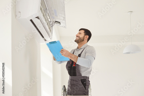 Happy worker handyman man checking, installing attaching wall air conditioning unit, AC repair, room temperature control, adjust optimal device performance, professional technician providing climate
