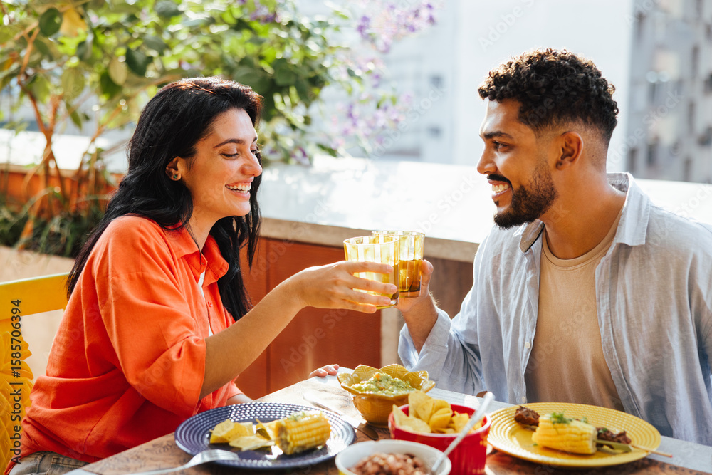 Latino couple enjoying lunch outdoors with drinks together Latino couple enjoying lunch outdoors with drinks together