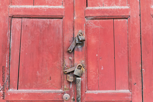 An old red wooden door locked with a lock