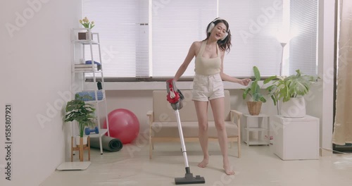 woman using vacuum cleaner to clean her house and listening music 