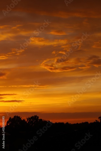 The sky is orange and the clouds are white. Phone wallpaper. Vertical background.