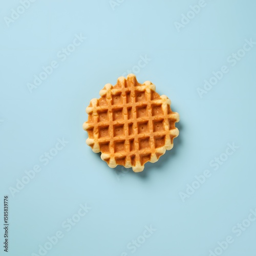 A single round waffle on a light blue background. The waffle has a golden brown color and a grid pattern. 