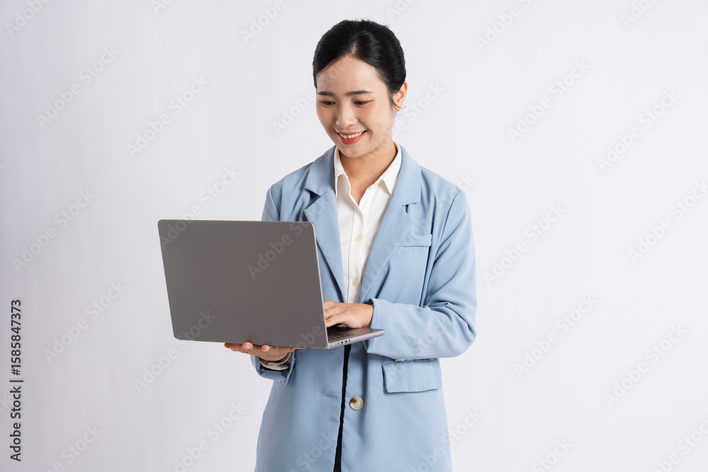 Young Professional Smiling While Working on Her Laptop in a Bright Studio Light Blue Business Suit Young Professional Smiling While Working on Her Laptop in a Bright Studio Light Blue Business Suit
