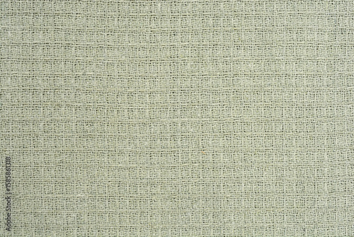 A uniform, close-up shot captures the subtle textured grid pattern of a light sage green waffle-weave fabric