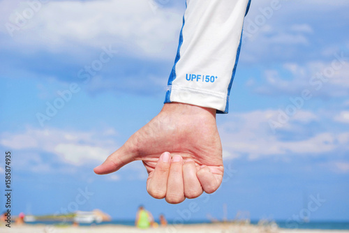 Close-up of a hand wearing a white protective sleeve with UPF 50 for high ultraviolet protection