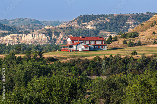 A gorgeous view of the Chateau DeMores in a surrounding of mountains, trees, and blue sky, situated near the entrance to Theodore Roosevelt National Park. State Historic Site, Medora, North Dakota, US