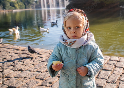 A little girl is standing on a stone walkway next to a pond