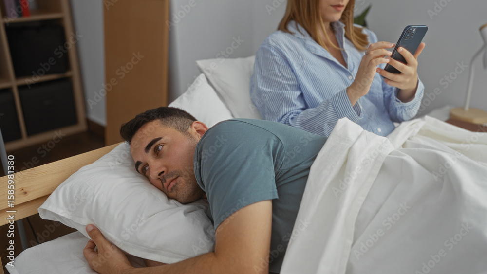 Obraz premium Couple in bed with woman using phone while man looks away reflecting on relationship in cozy bedroom setting indoors during morning light together happy love serene calm.