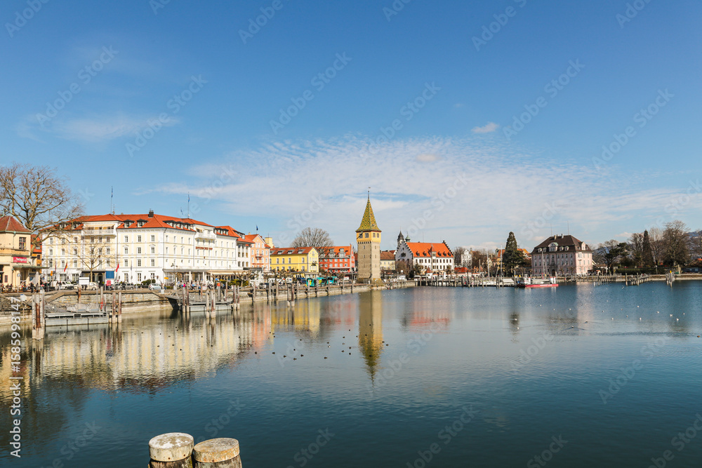 Obraz premium A Lindau city on Bodensee in Bayern Germanywith a large tower in the middle of it the panorama of the building is reflected in the calm water.