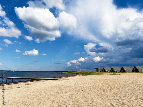 Beautiful calm landscape, seascape, camping, sunny beach, pier, dramatic cloudy blue sky.