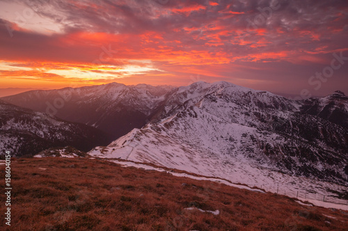 Aerial view of snow-capped peaks kissed by a fiery sunset, casting shadows across the majestic landscape, Zakopane, WojewÃ³dztwo maÅ‚opolskie, Poland.