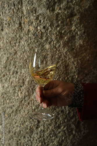 Hand swirling glass of white wine in wine cellar with moody lighting