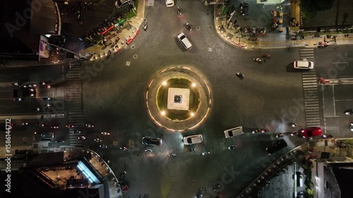Yogyakarta, Indonesia - 7 June 2023: A vibrant aerial night shot of the iconic Tugu Yogyakarta monument, glowing at the center of a bustling roundabout with streams of city traffic
