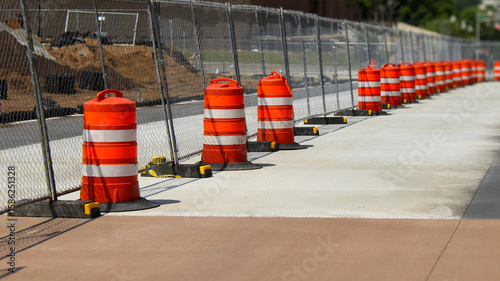 a construction site with infrastructure work and a closed off street. traffic barrels and fencing. background or transportation banner