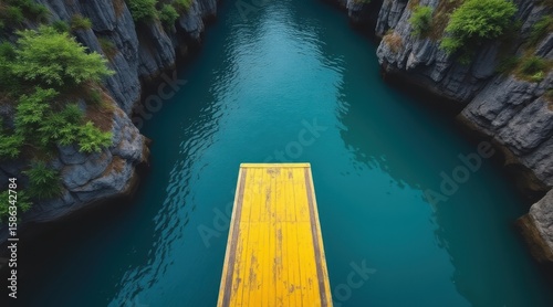 Yellow diving board poised over a stunning turquoise canyon lake with lush green vegetation