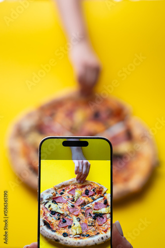 Smartphone capturing pizza moment – top view