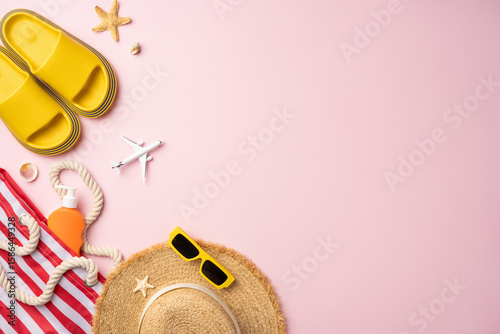 Yellow sandals, hat, sunglasses, toy airplane, and summer items perfectly arranged on pink background