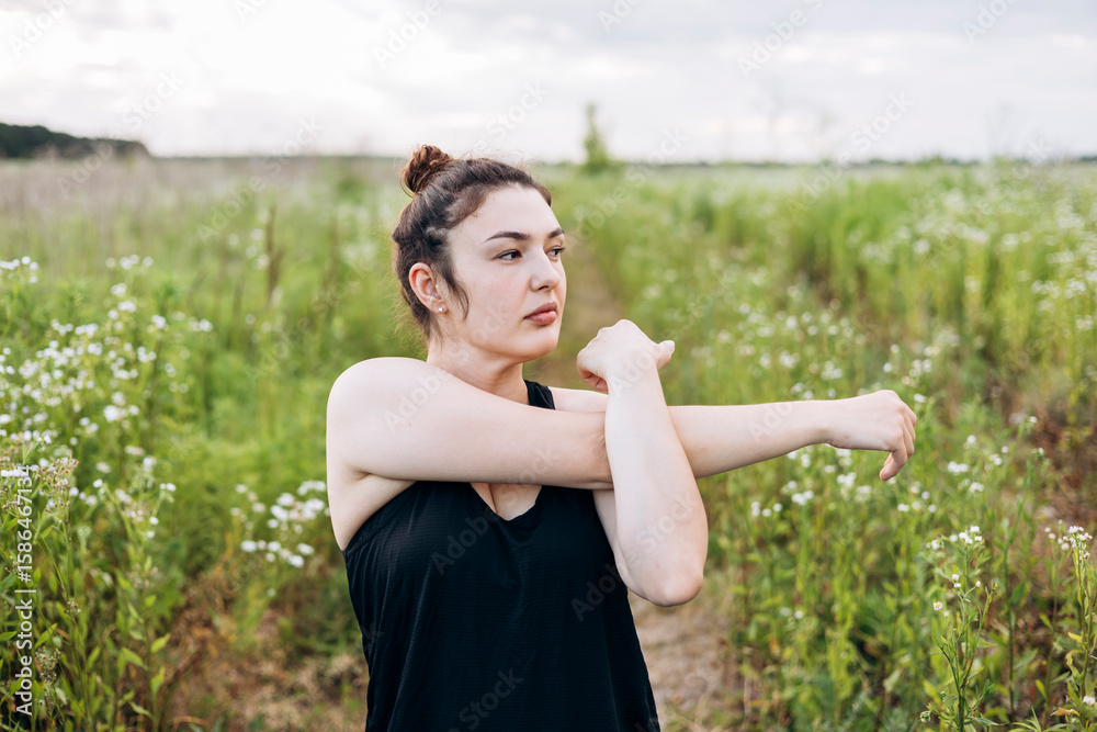 Woman stretching arms outdoors in a green field Woman stretching arms outdoors in a green field