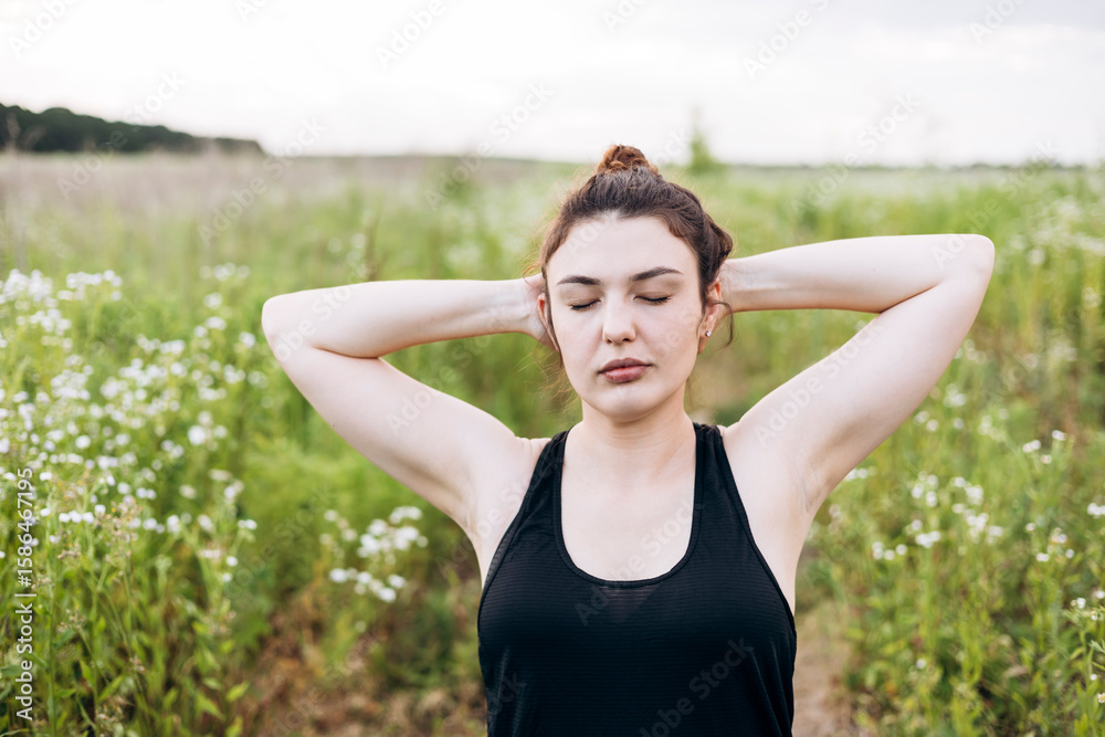 Woman meditating outdoors with arms behind her head Woman meditating outdoors with arms behind her head