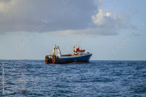 Fishing vessel is conducting an industrial catch of wild marine products using deep-sea trawl.