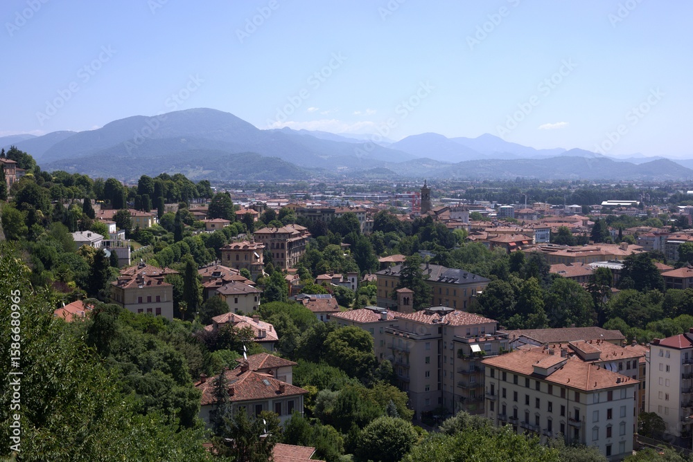 Fototapeta premium Panoramic green cityscape of Bergamo, Lombardy, Italy with hill and Alps view, Upper Town (Città Alta)