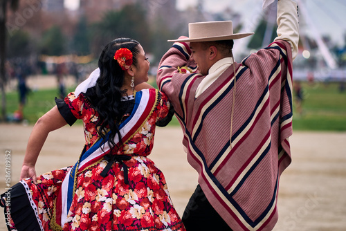 Portrait of a smiling young couple dressed as Chilean huasos, posing and joyfully dancing cueca outdoors. Traditional Chilean dance. Chilean traditions, celebrations, and culture.