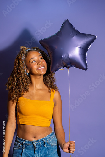 Young woman holding star shaped balloon expressing happiness and joy