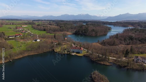 Scenic aerial view of Schloss Hartmannsberg, a former moated castle nestled between Schlosssee and Langbuergner See in Bavaria. A charming blend of history and nature near Bad Endorf, Germany. 