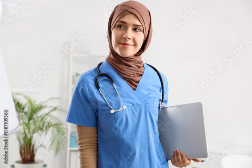 Female Muslim doctor with laptop in clinic