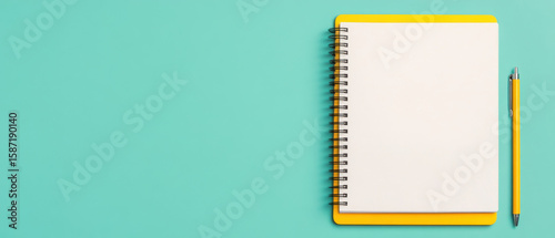 Blank spiral notebook with yellow cover and matching yellow pen on turquoise background, ready for creative ideas and notes