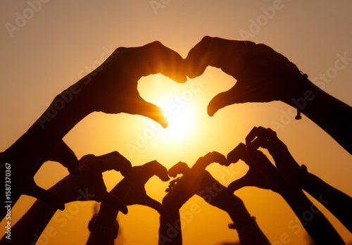 Multiple Hands Forming Heart Shapes Against Golden Sunset