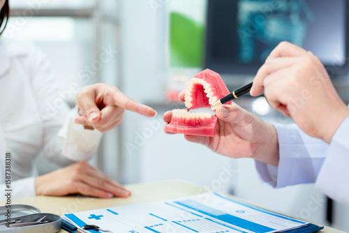 Billede på lærred An Asian male dentist explains dental health to a middle-aged Asian female patie