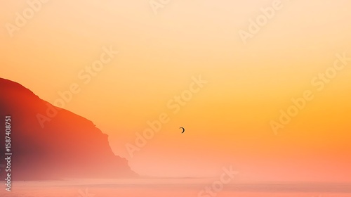 Lone kite surfer rides gentle waves under a fiery sunset sky