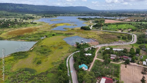 Drone footage of aerial view of Lam Phra Phloeng reservoir and surrounding farmland in Wang Nam Khiao, Nakhon ratchasima, Thailand. Scenic landscape of countryside with curved rural roads 
