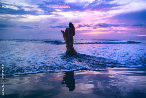 Obraz na plátně Woman in Saree Standing in Ocean at Sunset